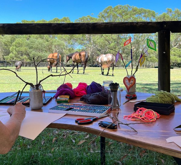 A table of art supplies overlooking a paddock full of horses