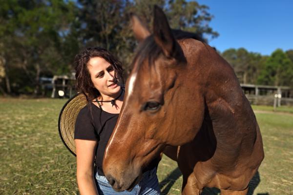 A Hoofbeats volunteer scratching the neck of Mack, one of the horses in the herd