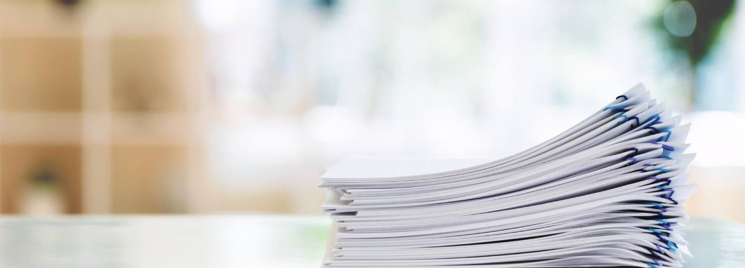 A stack of paperclip-bound paper reports, again a blurred background