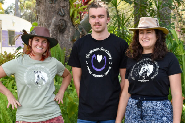 Three people wearing our Hoofbeats shirts, in black and avocado green
