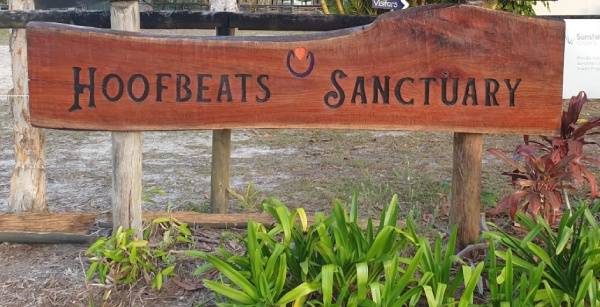 A wooden sign which reads Hoofbeats Sanctuary