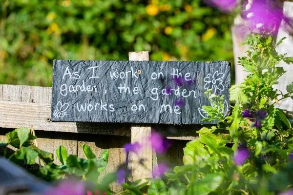 A sign in a garden read which reads 'As I work on the garden, the garden works on me'